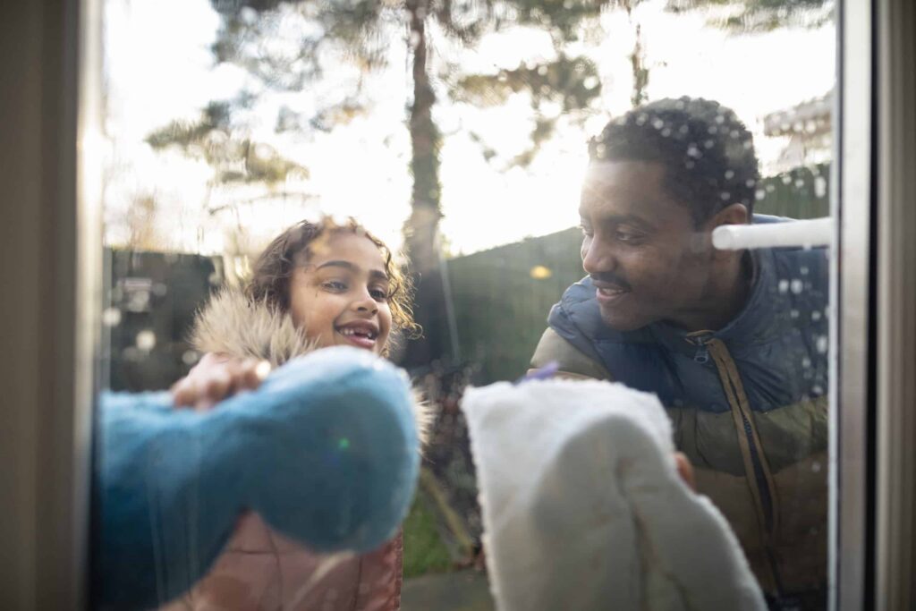 Father and daughter washing windows together