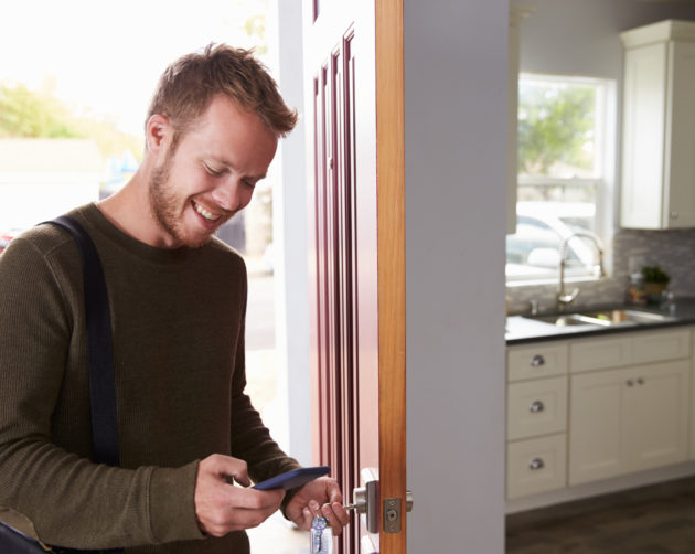 man entering front door of flat receiving text message