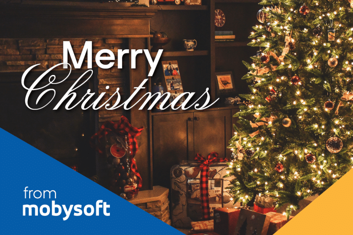 A warmly lit Christmas tree with ornaments stands beside a fireplace. Wrapped gifts are placed nearby. "Merry Christmas" text is overlaid in white. The bottom left corner features a blue section with "from mobysoft" written in white. ©Mobysoft