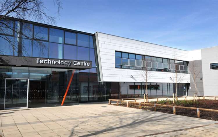 Modern building with large glass windows and a sign reading "Technology Centre." The structure is surrounded by a paved area and minimal landscaping under a clear blue sky. ©Mobysoft