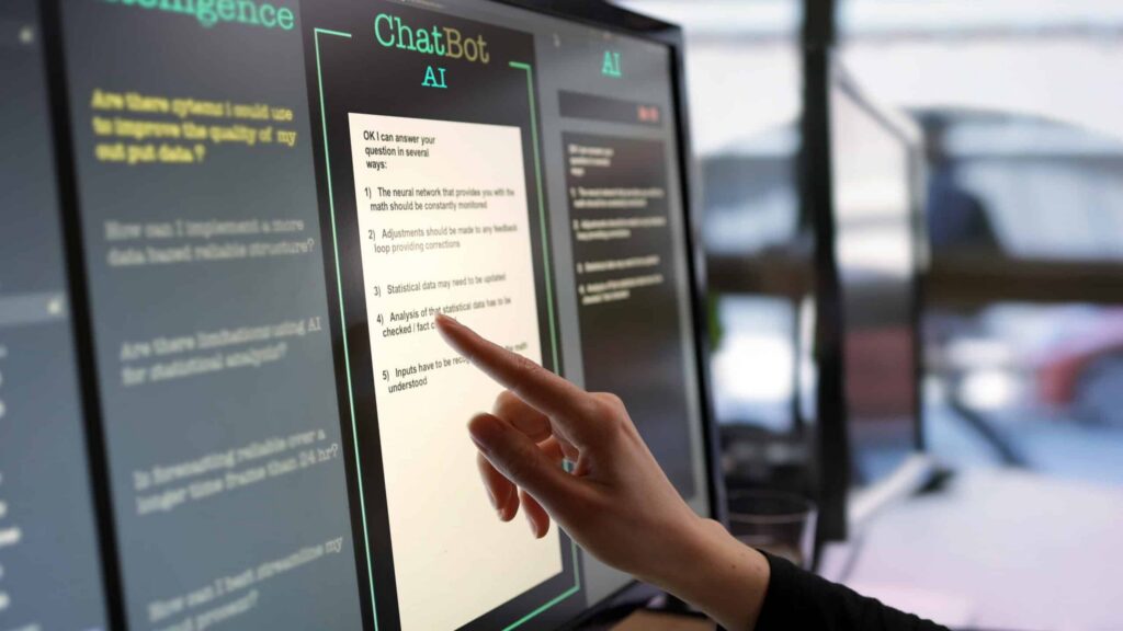 A person's hand points at a computer screen displaying a chatbot interface, where AI explainability features highlight chat interactions and options. The ambient lighting is dim, underscoring the focus on the illuminated explanations provided by advanced algorithms. ©Mobysoft