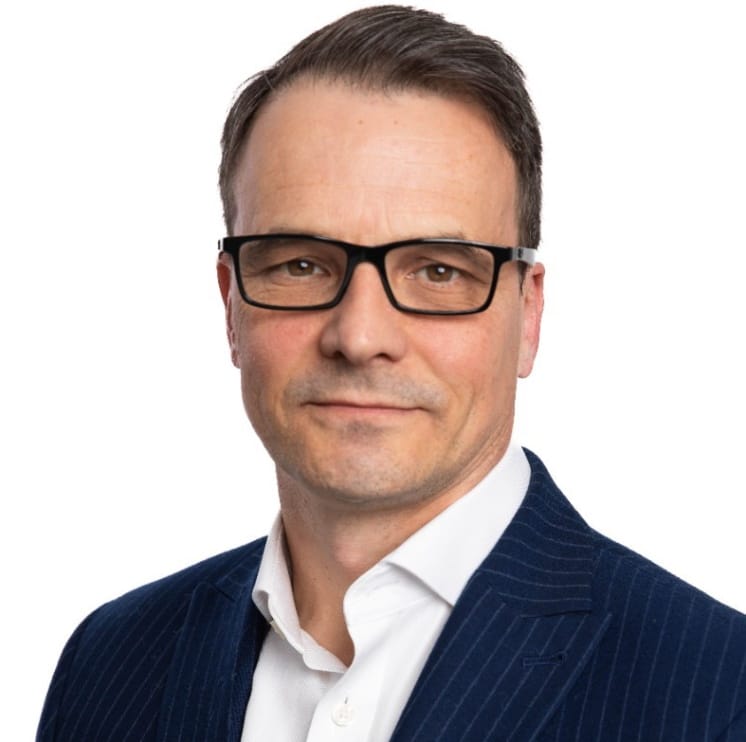 A Chief Marketing Officer wearing glasses and a dark, pinstriped suit with a crisp white shirt stands against a plain white background. ©Mobysoft