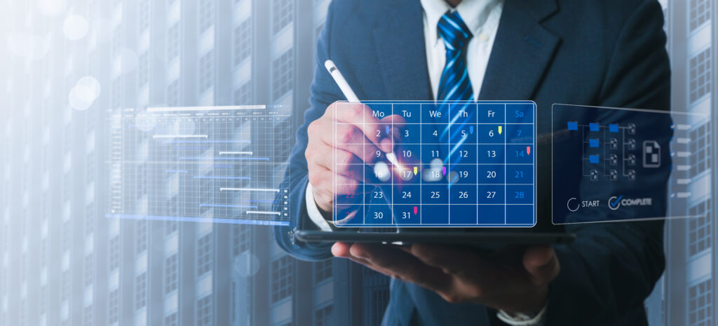 A person in a suit uses a stylus to interact with a digital calendar on a tablet, seamlessly integrating data strategy into their daily routine. The transparent interface displays days of the week and technology icons, suggesting a futuristic or tech-focused environment. ©Mobysoft