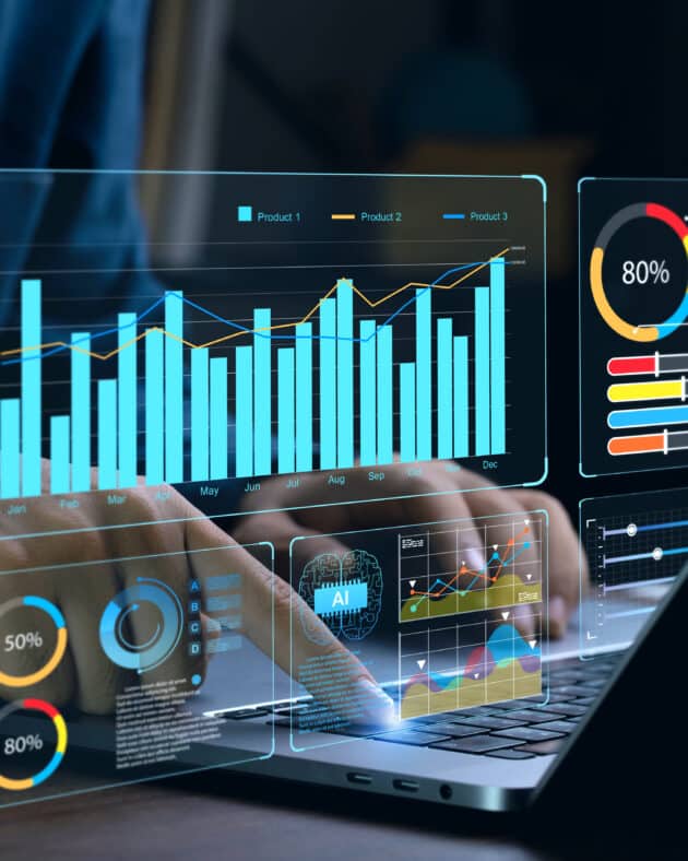Hands interact with a laptop featuring holographic charts and graphs. Displays include bar graphs, pie charts, and percentage data, each showing diverse analytics essential for data-driven social housing repairs, reflecting advanced data visualization or financial analysis. ©Mobysoft